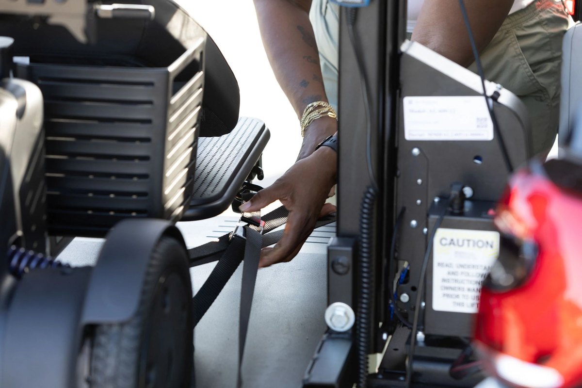 Hands fastening a strap to a scooter on the AL600 platform