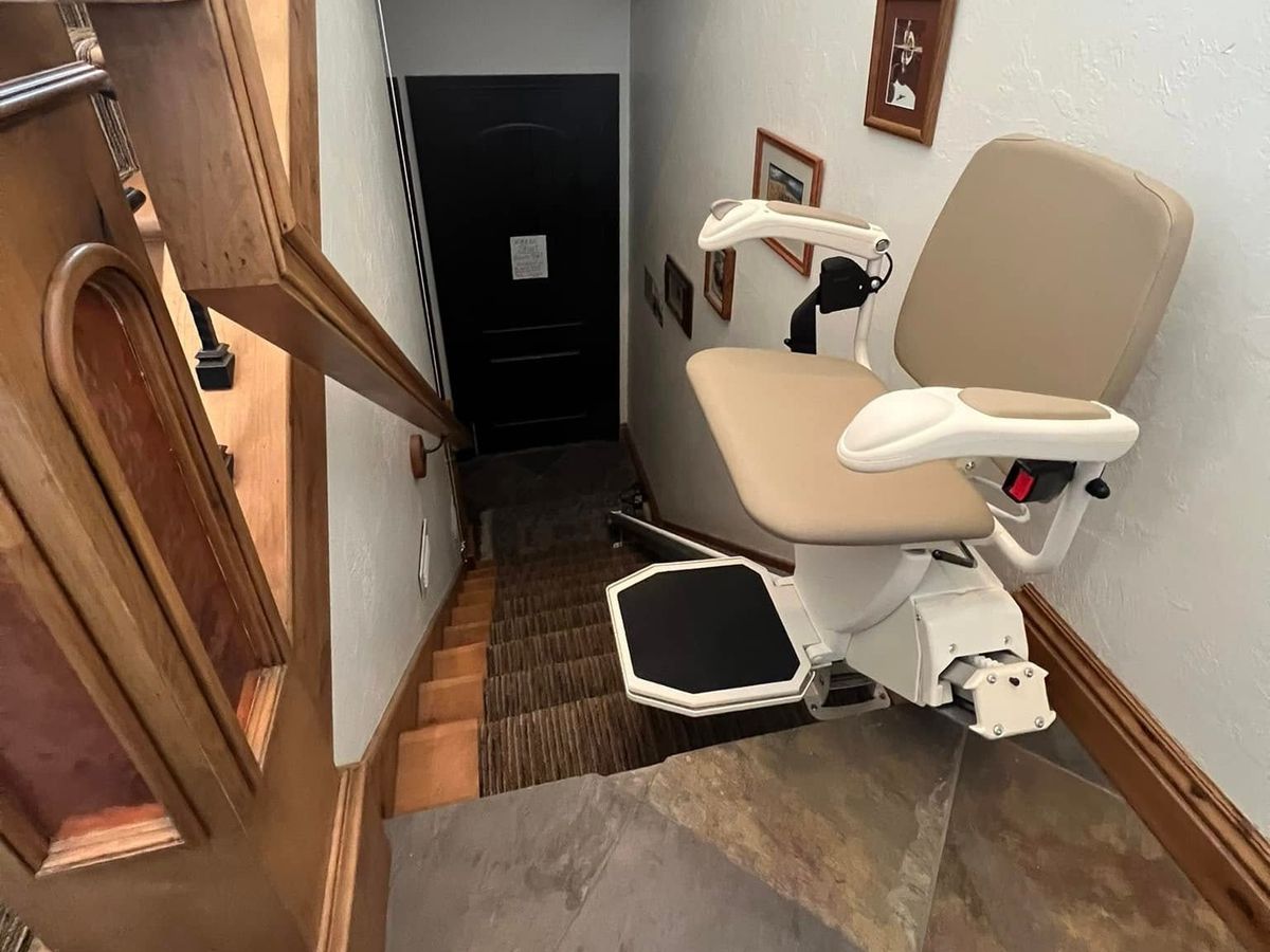 Lazo install: tan-seated lift at the bottom of a short flight beside a dark doorway and wood railing