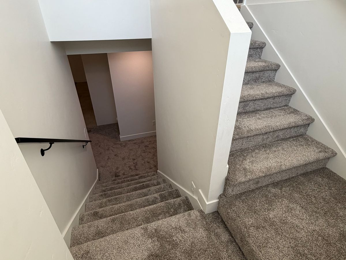 The same carpeted staircase with a black handrail, before the stair lift