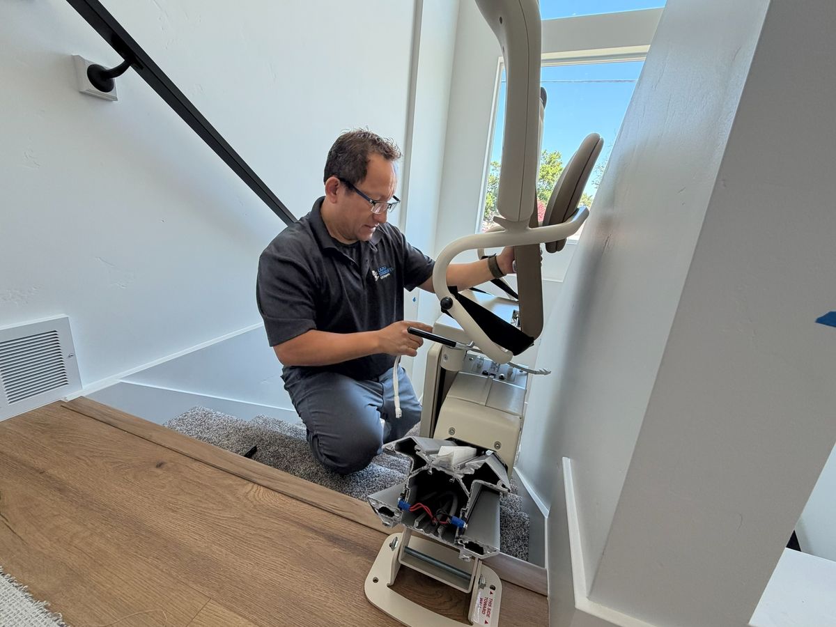 Lazo installer kneeling on the landing, assembling the stair lift seat at the top of the stairs