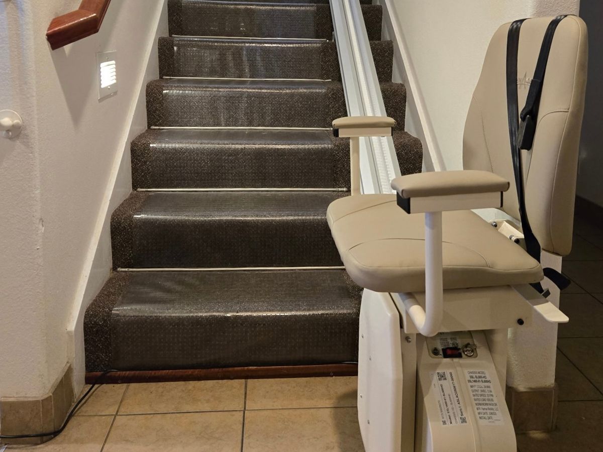 Harmar SL600HD heavy-duty stair lift parked on the tiled floor at the bottom of the stairs