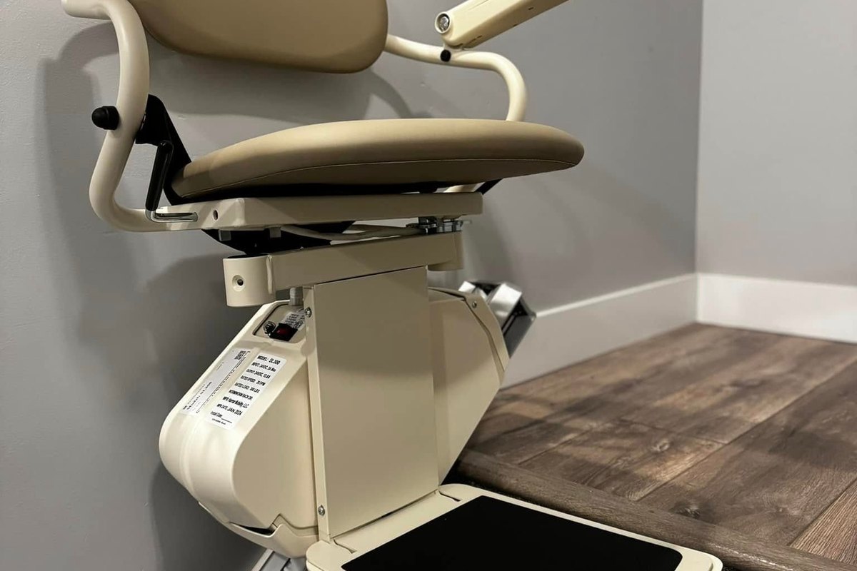 Harmar SL300 stair lift parked at the head of a carpeted flight beside a gray wall