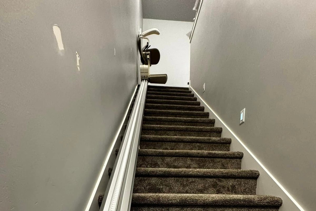 Carpeted basement flight with an SL300 rail along the wall and the lift parked at the top