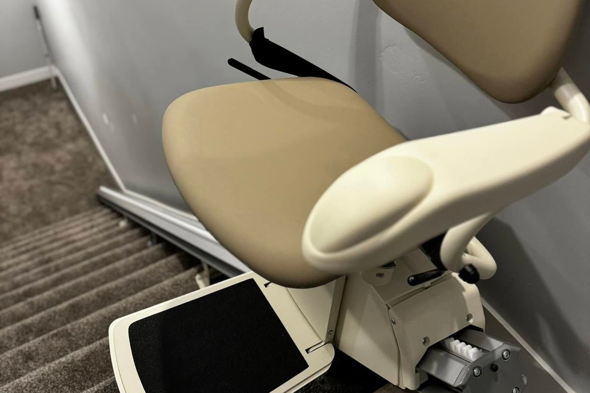 Harmar SL300 stair lift with its seat, armrests, and footrest down at the foot of a stairwell