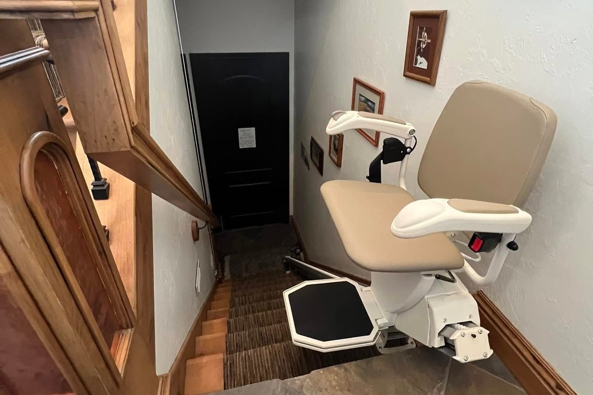 Harmar SL600 stair lift parked at the head of a basement flight on a tiled landing