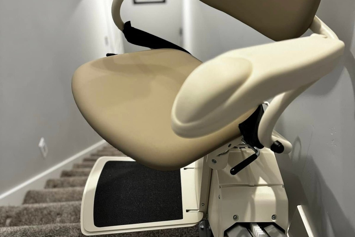 Seat and footrest of a Harmar SL300 stair lift installed at the top of a gray stairwell