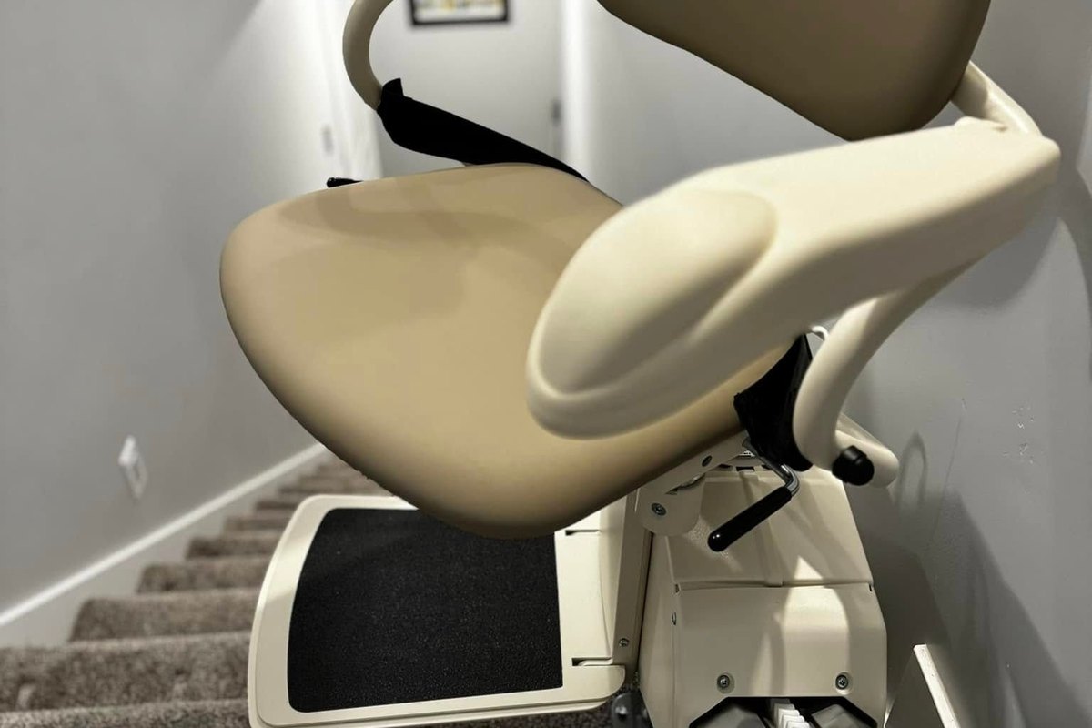 Harmar SL300 stair lift ready at the top of a carpeted stairwell, footrest down