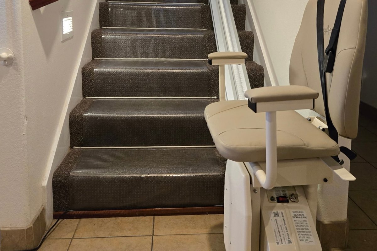 Seat, armrests and carriage of an SL600HD heavy-duty lift parked beside the bottom step, tiled floor below